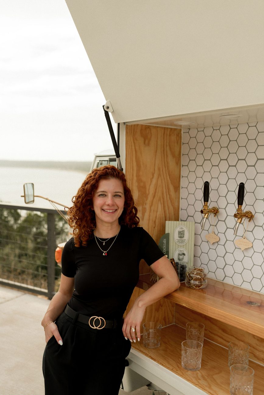 Veronica Fossi, co-founder of Uphill Taps, leaning against the open Piaggio Tap Bar with brass taps visible.